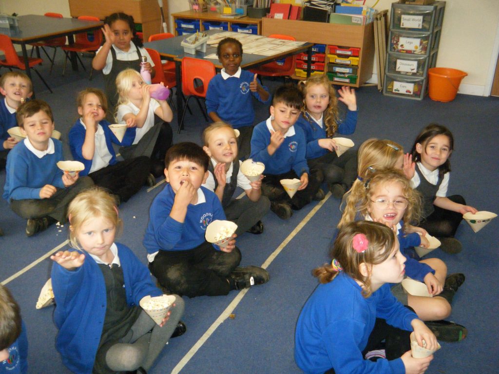 Year 1 pupils sitting on the floor and eating popcorn