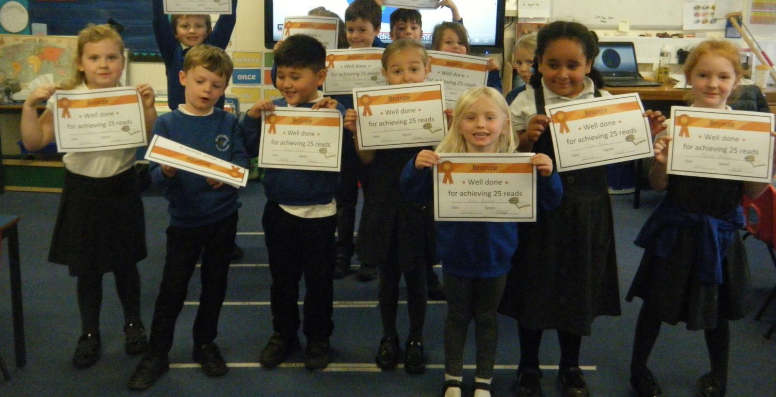 Banner photo of year 1 pupils holding their reading certificates